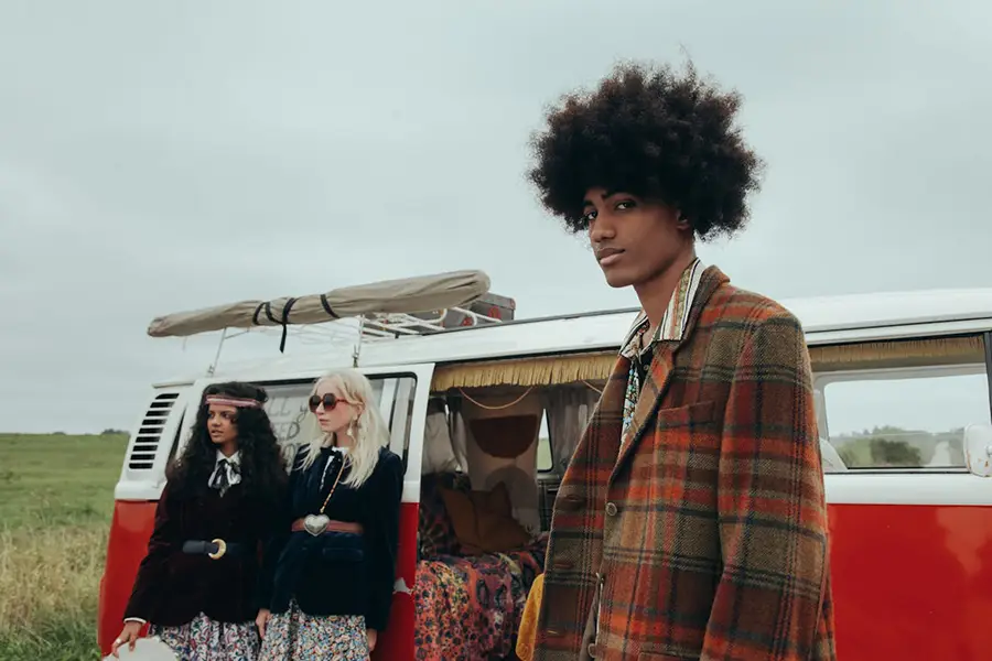 Mann mit karierter Jacke und zwei Frauen an einem Bulli